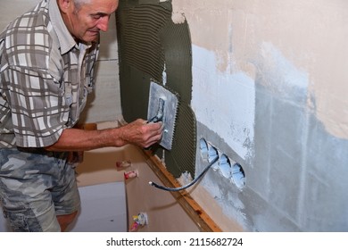 The Tiler Glues And Lays The Tiles On The Wall Under The Kitchen Counter