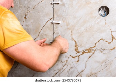 Tiler installing leveling system tiles on wall.