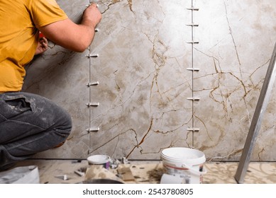 Tiler installing leveling system tiles on wall.