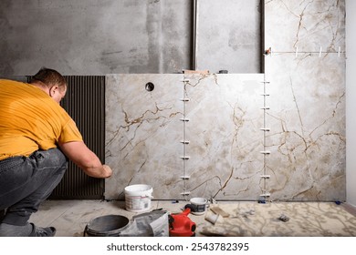 Tiler installing leveling system tiles on wall.