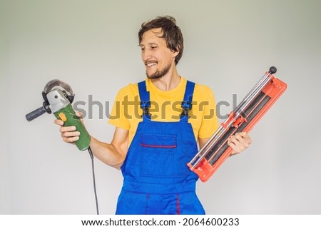 A tiler, a tiling specialist, holds a tile cutter in his hands