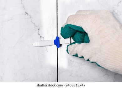 Tiler's hand installing leveling system tiles.