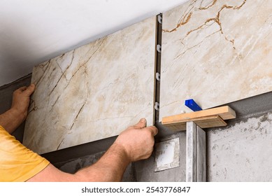 Tilers installing large format tiles on wall. 