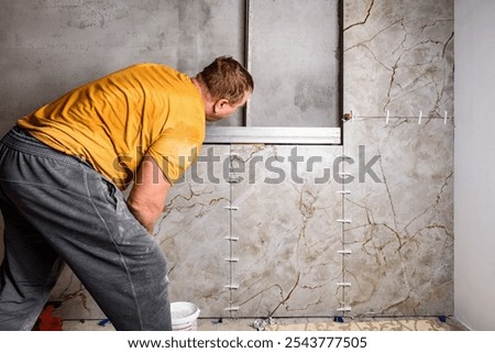 Tilers installing large format tiles on wall. 