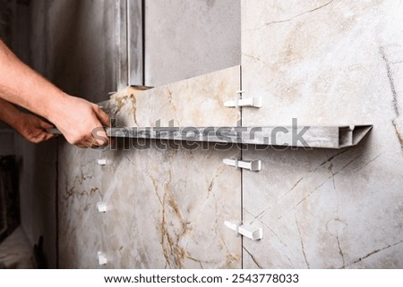 Tilers installing large format tiles on wall. 