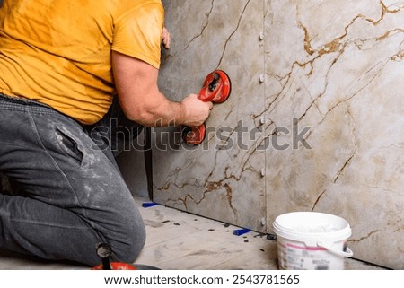 Tilers installing large format tiles on wall. 