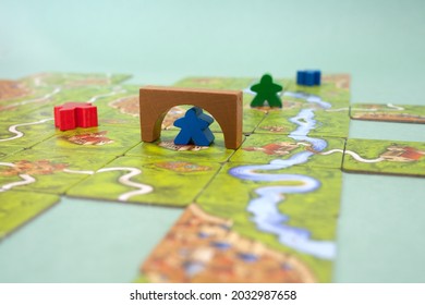 The tiles and meeples of tabletop boardgame Carcassonne with a roads and castles and river. Popular family hobby board game. Minsk, Belarus - July 10, 2021 