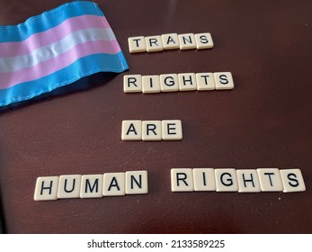 Tiles Spelling Trans Rights Are Human Rights On A Table With A Transgender Pride Flag