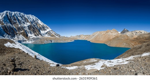 Tilicho lake with still and bright blue water in calm weather in autumn sunny day. A sacred to Buddhists and Hindus lake in Himalaya mountain in Annapurna area, Nepal.