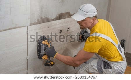 Tiling with large format tiles. A tiler placing a tile held by a tile suction cups.