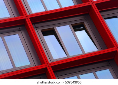 Tilt Close-up Photo Of Ajar Windows In Red Frames. Optimistic Abstract Image On The Subject Of Modern Architecture. Residential Or Office Building Exterior Detail.