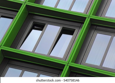 Tilt close-up photo of ajar windows in green frames. Eco-friendly technologies / energy saving motif. Building exterior detail. Abstract photo on the subject of modern architecture.