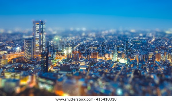 Tilt shift Photo High-rising buildings lighting up\
in tokyo