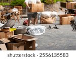 tilt shift shot of household stuff on the floor and a man carrying box