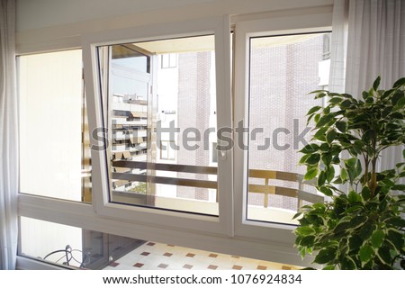 Tilt-and-turn white pvc window in living room, opened