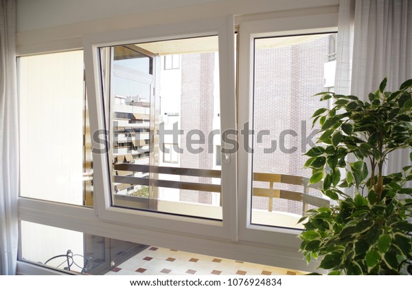 Tilt-and-turn\
white pvc window in living room,\
opened