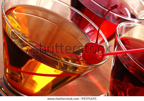 Tilted composition of cocktail drinks with backlighting and abstract reflections.  Macro with shallow dof.  Selective focus on the cherry.