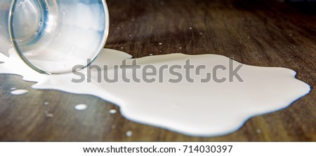 a tilted glass with milk is lying on a table