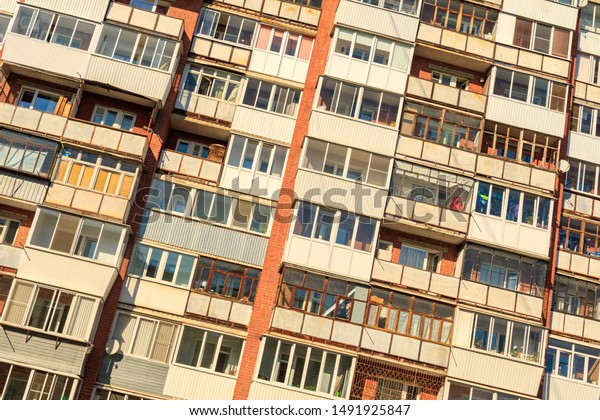 tilted photo with a large number of balconies on the wall of a multi-storey building. balcony of different design and glazing ugly design of the city