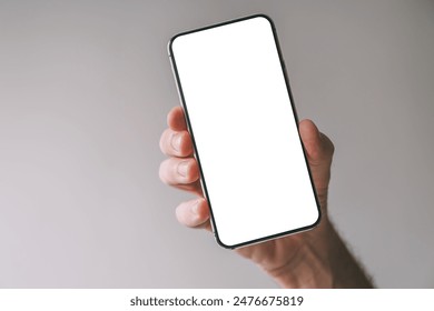 Tilted vertically held smartphone with blank white mockup screen in male hand, selective focus