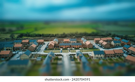 Tilt-shift aerial view of a suburban neighborhood with houses and roads, creating a miniature effect.