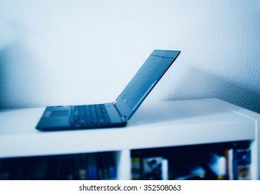 Tilt-shift lens focus on ultra thin laptop in modern interior home office. Blue technological ligt and tilt-shift lens used to outline the computer.
