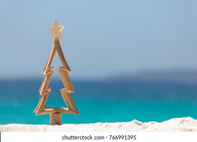 Timber Christmas Tree With Star Sits In Pristine White Sand With Idyllic Beach Background.  A Summer Christmas.  