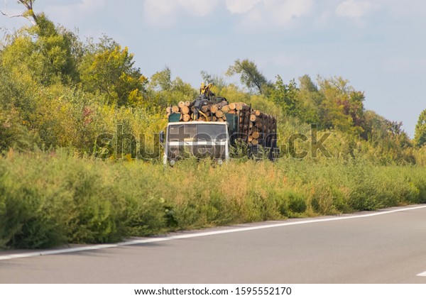 A timber truck with wood travels along a\
highway with cargo, harvesting and delivery of sawn timber to a\
customer at a destination for further processing for industrial\
purposes.