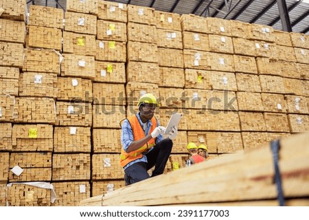 A timber yard worker meticulously measures lumber in the foreground, while his colleague verifies data on a tablet in the background, a testament to the precision and teamwork