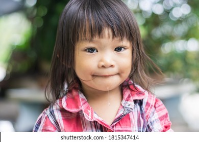 Portrait​ image​ of​ 2-3​ years​ old​ baby.​ Face​ of Happ​y Asian​ child​ girl​ smiling​ and​ looking​ camera​ man.​ At​ the​ green​ backyard​ garden.​ Relaxing​ time.