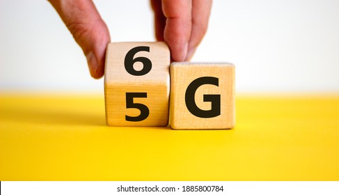 Time to 6G symbol. Male hand turns wooden cube and changes sign 5G to 6G. Technology, business, network, communication and 6G concept. Beautiful yellow table. White background, copy space.