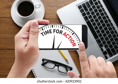 TIME FOR ACTION message on hand holding to touch a phone, top view, table computer coffee and book