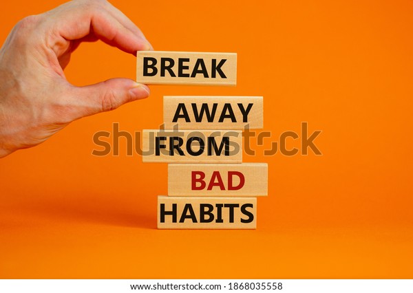 Time to break bad\
habits. Wooden blocks with words \'break away from bad habits\'. Male\
hand. Beautiful orange background, copy space. Business and\
psychological concept.
