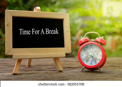 TIME TO A BREAK! inscription written on chalkboard and red alarm clock on  old wooden desk . Time concept. - Shutterstock ID 582055708