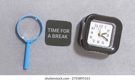 Time for a break reminder rests between a blue handled magnifying glass and a square black travel alarm clock symbolizing the importance of pausing work to re-examine priorities and recharge energy.