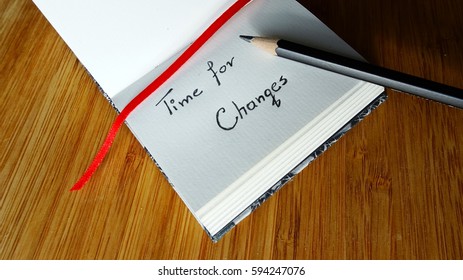 Time for Changes, Small notebook and pencil on wooden background.