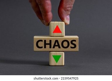 Time to chaos symbol. Businessman holds a wooden cubes with up icon. Wooden cubes with the concept word Chaos. Beautiful grey table grey background. Business and chaos concept. Copy space.