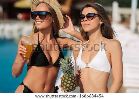 Time for chiling on beach! Two sexy girls wearing stylish swimwears and having fun, moving, dancing near pool