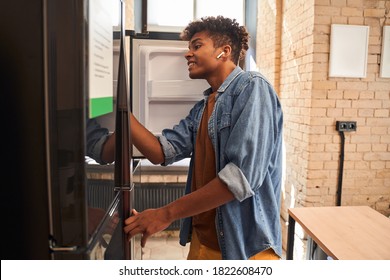 Time To Cleaning! Curly Haired Man Looking At The Refrigerator And Wipes It. Restaurant Business, Working In A Restaurant Concept