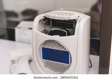 Time clock attendance machine with open cover showing internal mechanism, highlighting maintenance, repair, servicing and office equipment inspection.