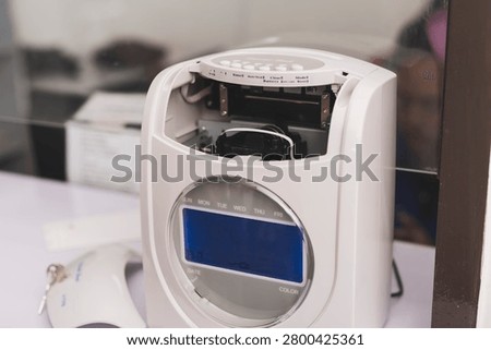 Time clock attendance machine with open cover showing internal mechanism, highlighting maintenance, repair, servicing and office equipment inspection.