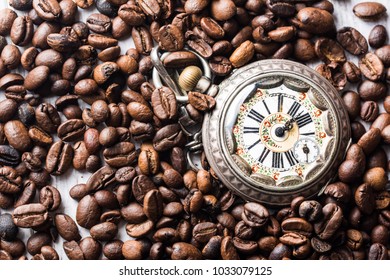 Time to coffe.Coffee beans with clock on the table