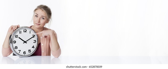 Time Concept - Smiling Beautiful Young Blond Woman Pointing At A Clock, Showing Patience And Relaxed Management Of Deadlines, White Copy Space, Long Banner