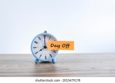 Time for day off concept with a message on Day Off written on the paper sticker and stick to the alarm clock.  Noise is visible due to the texture of the subjects - Shutterstock ID 2015479178
