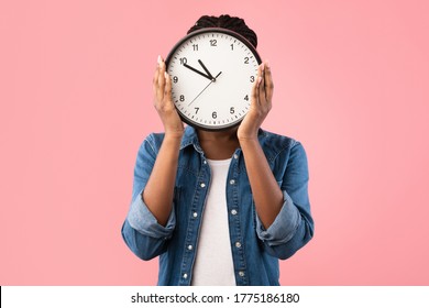 Time And Deadline. African Girl Holding Clock In Front Of Face Standing On Pink Studio Background.