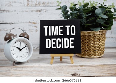 Time to Decide text with alarm clock on wooden background