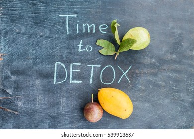 TIME TO DETOX chalk inscription on the wooden table fruits: mango, passion fruit and guava. Health Concept.