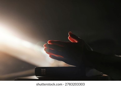 A time of devout prayer illuminated by bright light, the holy Bible, and a spiritual worship background
