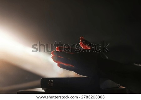 A time of devout prayer illuminated by bright light, the holy Bible, and a spiritual worship background
