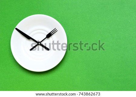 Time to eat and diet concept, plate as a clock on the green background. Place for text.